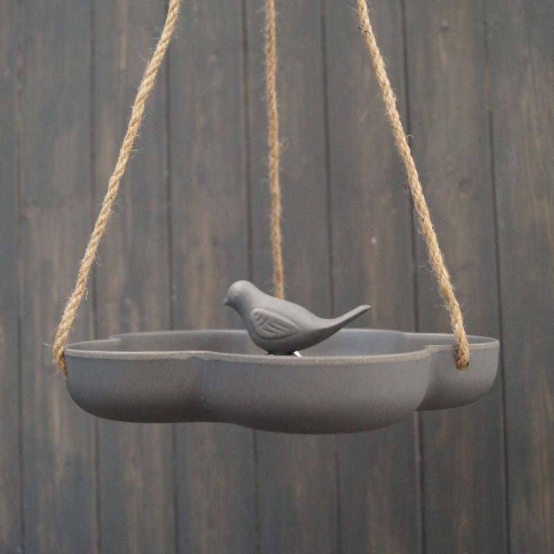 The Earthy Anthracite Bamboo Hanging Bird Bath/Feeder W23.3cm is a gray, frost-proof ceramic feeder with a bird figurine in the center, suspended by ropes against dark wood.