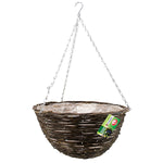 The Marksman Rattan Garden Hanging Basket 14" showcases a contemporary rattan design with a brown wicker construction and a clear plastic liner. Suspended by three metal chains attached to a hook, it's ideal for any outdoor space. Additionally, it includes a small green and white product tag attached.