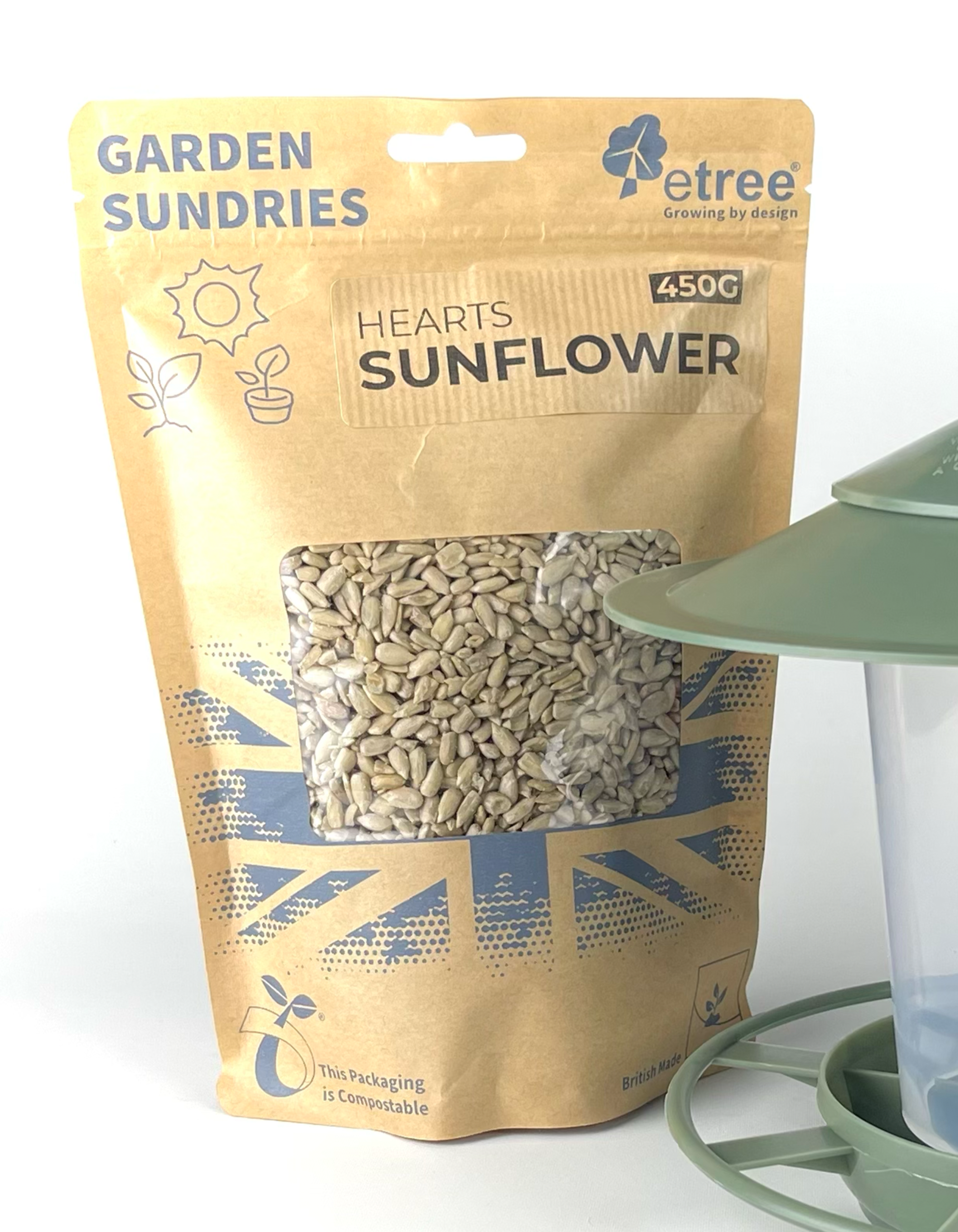 A 450g "Premium Sunflower Hearts" package from etree, featuring a brown compostable bag with blue sun and British flag designs, is next to a green bird feeder.