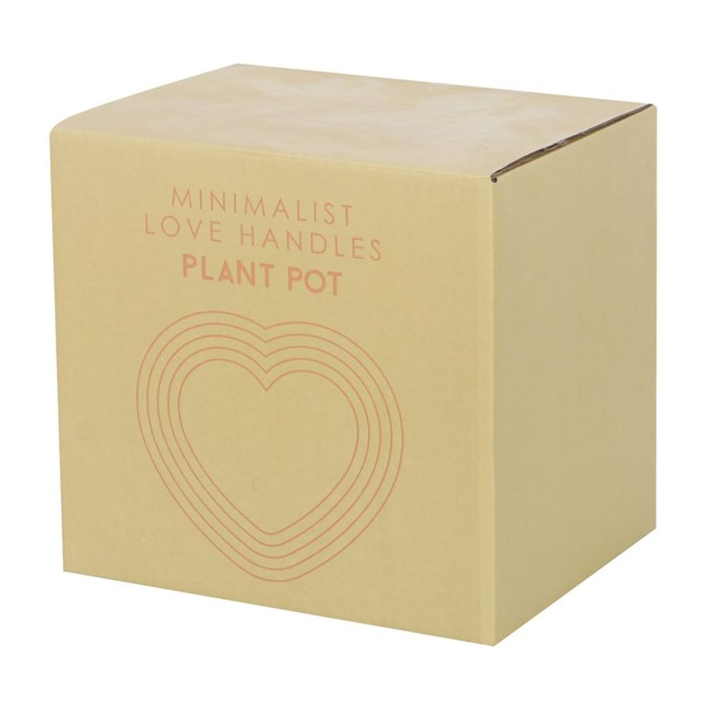 The packaging features a cardboard box with "Minimalist Love Handles Plant Pot" in orange text and a heart made of concentric lines. This simple design provides a glimpse of the quirky home decor within, ideal for those who enjoy unique items like the Cream Speckle Bum Plant Pot or other distinctive dolomite plant pots.
