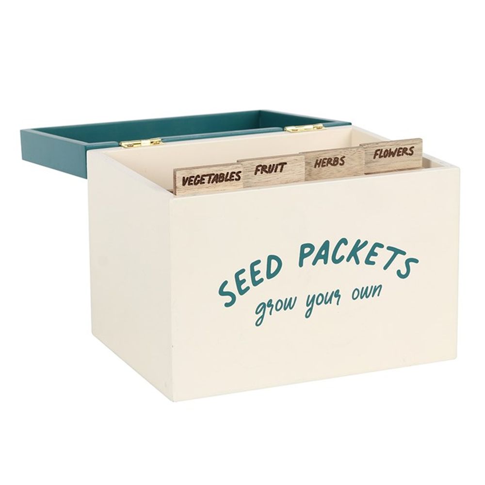 A cream-colored wooden Seed Packet Storage Box with a green interior features green typography that reads "Seed Packets, grow your own." Inside, labeled dividers for "Vegetables," "Fruit," "Herbs," and "Flowers" neatly organize the seed packets. The open lid elegantly showcases the organized compartments.