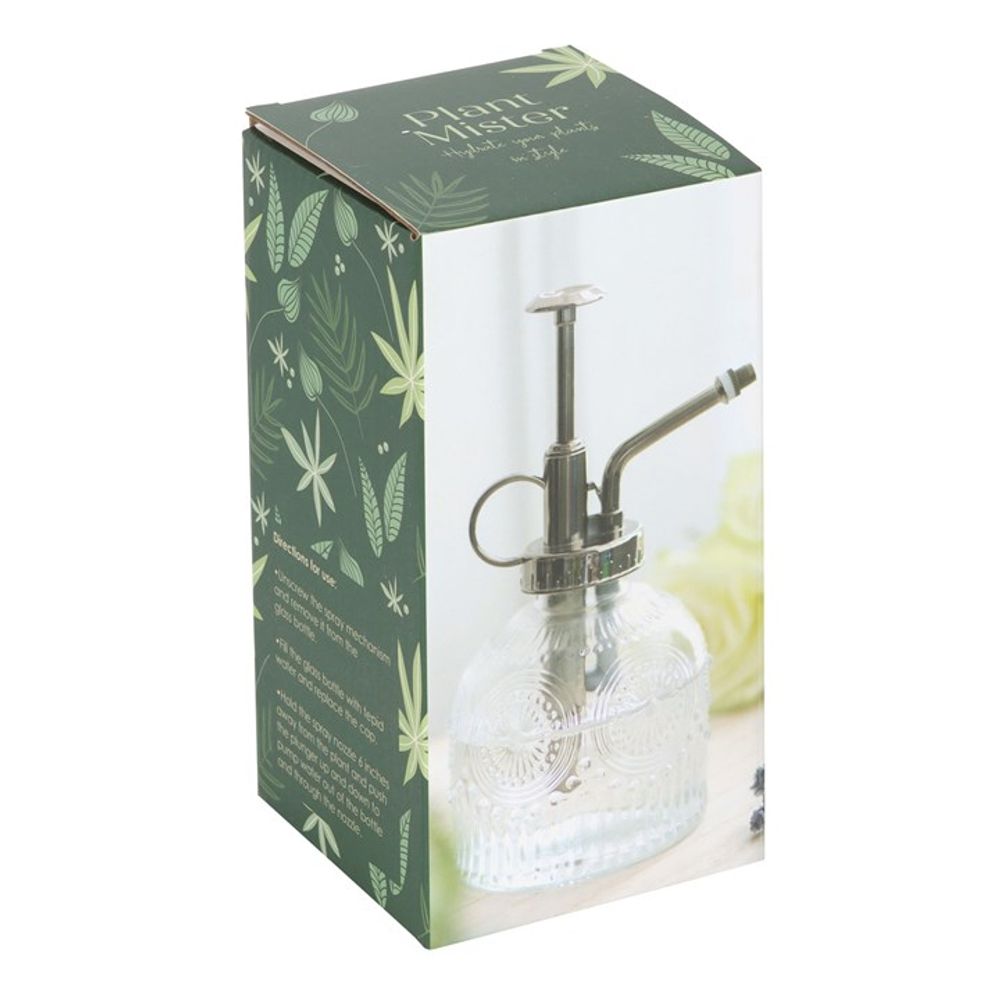 Add a vintage touch to your indoor garden with the Small Patterned Glass Plant Mister. Featuring a clear ornate glass bottle and silver pump, its classic allure is enhanced by green packaging adorned with leaf patterns and product information.