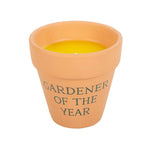 The Gardener of the Year Citronella Candle features vibrant yellow citronella wax in a rustic terracotta pot with elegant script, offering a lovely contrast for any ceramic plant pot display.