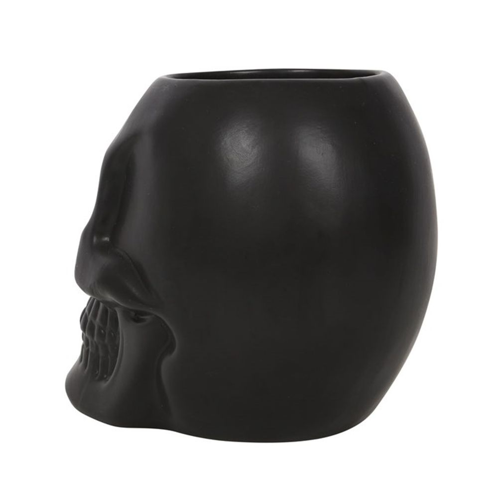The Black Skull Plant Pot is a black ceramic mug shaped like a skull, featuring detailed contours of the face, teeth, and eye sockets. With its matte finish, it makes an excellent addition to your home decor and is perfect for spooky house plants.