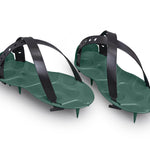 A pair of ProSpike Lawn Aerator Shoes featuring an enhanced strap design and four cross-shaped spikes on the soles. The black plastic adjustable straps ensure a secure fit over regular shoes, allowing the user to effortlessly aerate their lawn by walking on it.
