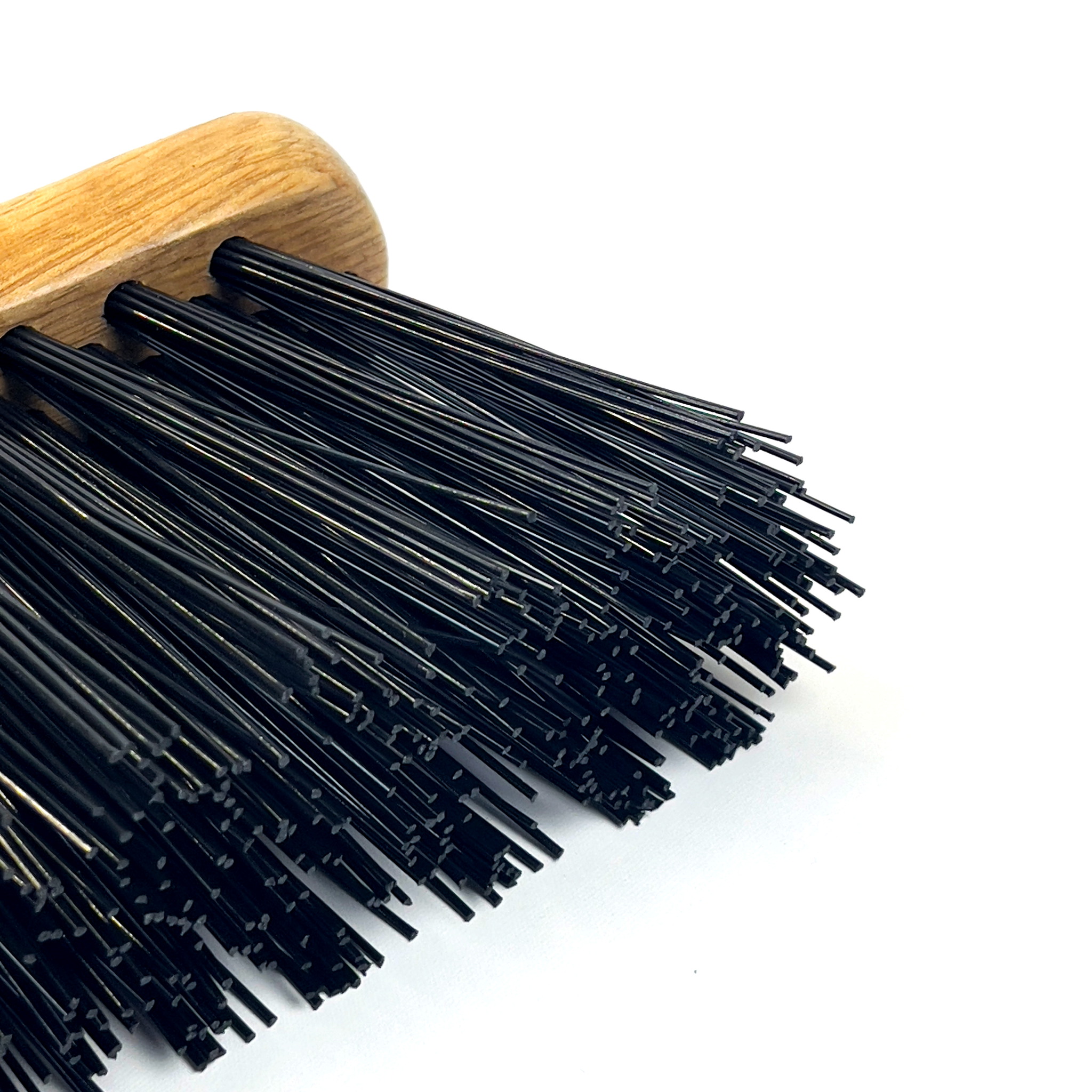 Close-up of a Hand Brush with Hard Bristles, featuring a wooden handle and densely packed, stiff black bristles. The straight, uniformly cut bristles are ideal for sweeping or scrubbing tough dirt. The white background accentuates the texture and detail of the brush.