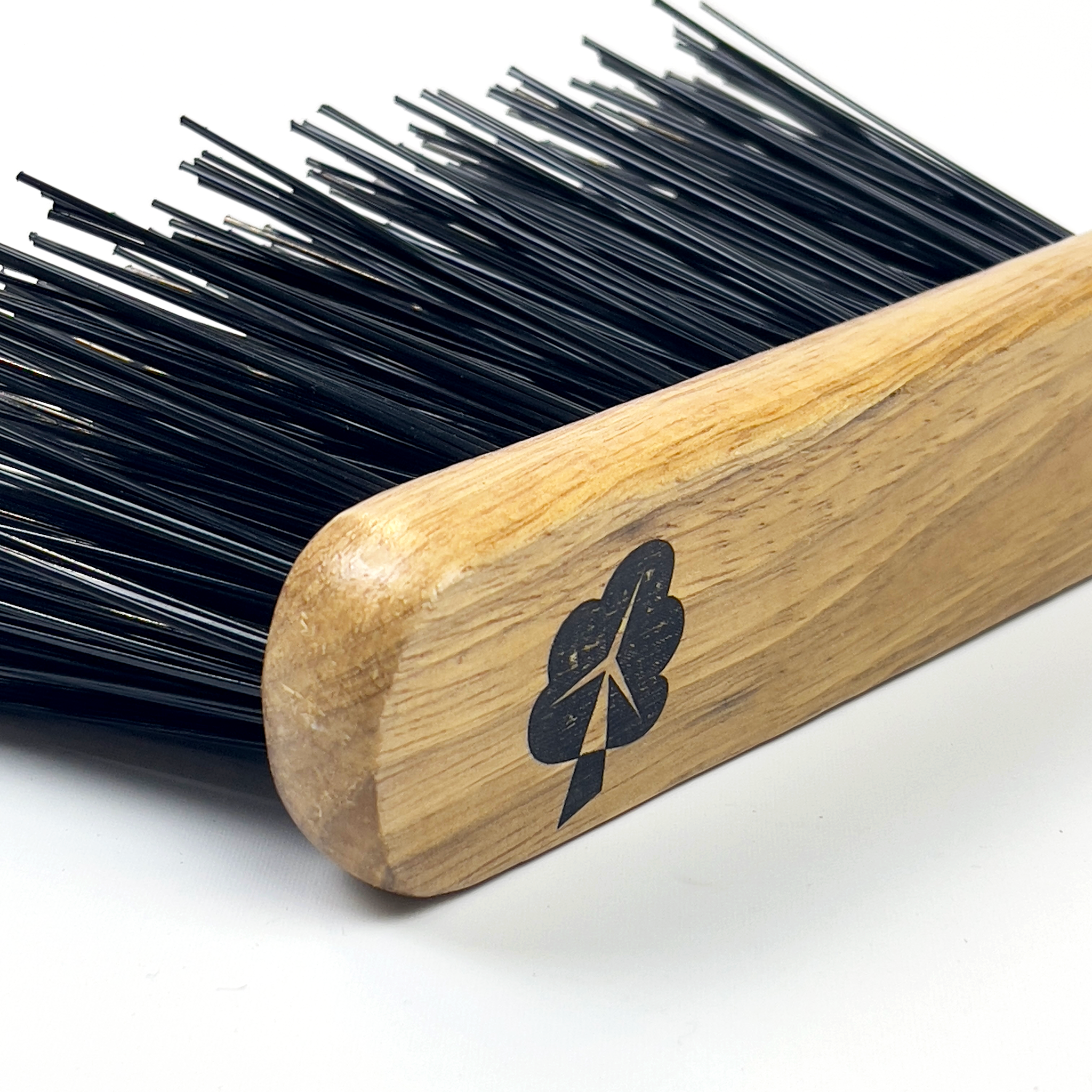 Close-up of a Hand Brush with Hard Bristles by etree, showcasing its sturdy black bristles and wooden handle adorned with a tree-shaped logo. The bristles appear slightly bent, while the handle boasts a smooth, polished finish. The backdrop is white.