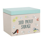 The British Garden Birds Seed Packet Storage Box is a beige box with a green lid, ideal for organizing garden seeds. It features charming illustrations of a robin, blue tit, and various flowers, making it an excellent gift for gardeners.