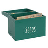 The Seed Storage Box, designed with a green exterior and partially open lid, showcases four included dividers labeled "VEGETABLES," "FRUIT," "HERBS," and "FLOWERS" for an organized way to store your seeds.