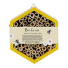 The Wooden Bee House is a hexagonal structure with multiple hollow tubes for solitary bees, featuring a yellow border and a label that reads "Bee house - Perfect for pollinators," adorned with charming bee and flower illustrations—ideal for any garden.