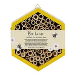 The Wooden Bee House is a hexagonal structure with multiple hollow tubes for solitary bees, featuring a yellow border and a label that reads "Bee house - Perfect for pollinators," adorned with charming bee and flower illustrations—ideal for any garden.