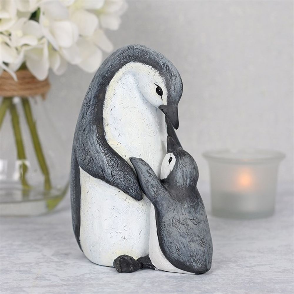 The "Mum Waddle I Do Without You" Penguin Ornament features a beautifully sculpted mother and chick penguin appearing to embrace. They stand in front of a glass jar filled with white flowers and a small candle on a textured surface, creating an ideal gift for any occasion.