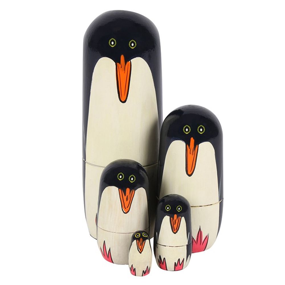 Introducing the Penguin Russian Doll set: a collection of five intricately handpainted wooden nesting dolls. Each penguin doll, crafted in varying sizes, showcases classic black and white colors, orange beaks, and bright yellow eyes. Arranged in descending size order from left to right, the smallest doll is nearly fully enclosed within the others.