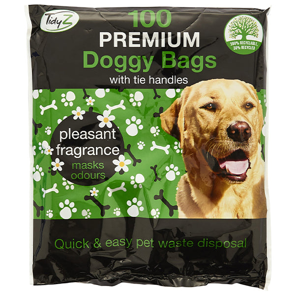 A package of "Tidyz Premium Extra Strong Doggy Bags 100 Pack" with durable tie handles. The packaging is primarily black and green with white paw prints and bones. It mentions "pleasant fragrance masks odors" and promotes "quick & easy pet waste disposal." Features a Labrador retriever image.
