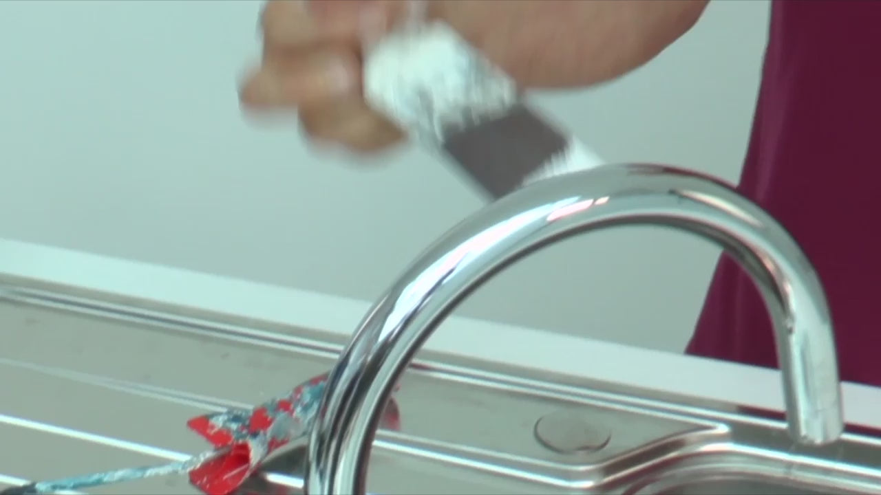 Demonstration of a plastic washboard being used to clean paint rollers and brushes under a running tap. 