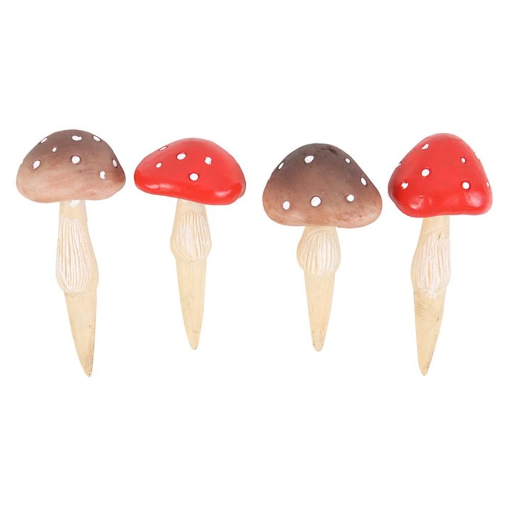 The "Set of 4 Mini Mushroom Plant Pot Pals" includes four small mushroom decorations with pointed bases. Two of the mushrooms feature brown caps adorned with white spots, while the other two have vibrant red caps with white spots. All mushrooms are designed with beige stems, making them ideal for adding a whimsical touch to a plant pot or fairy garden.