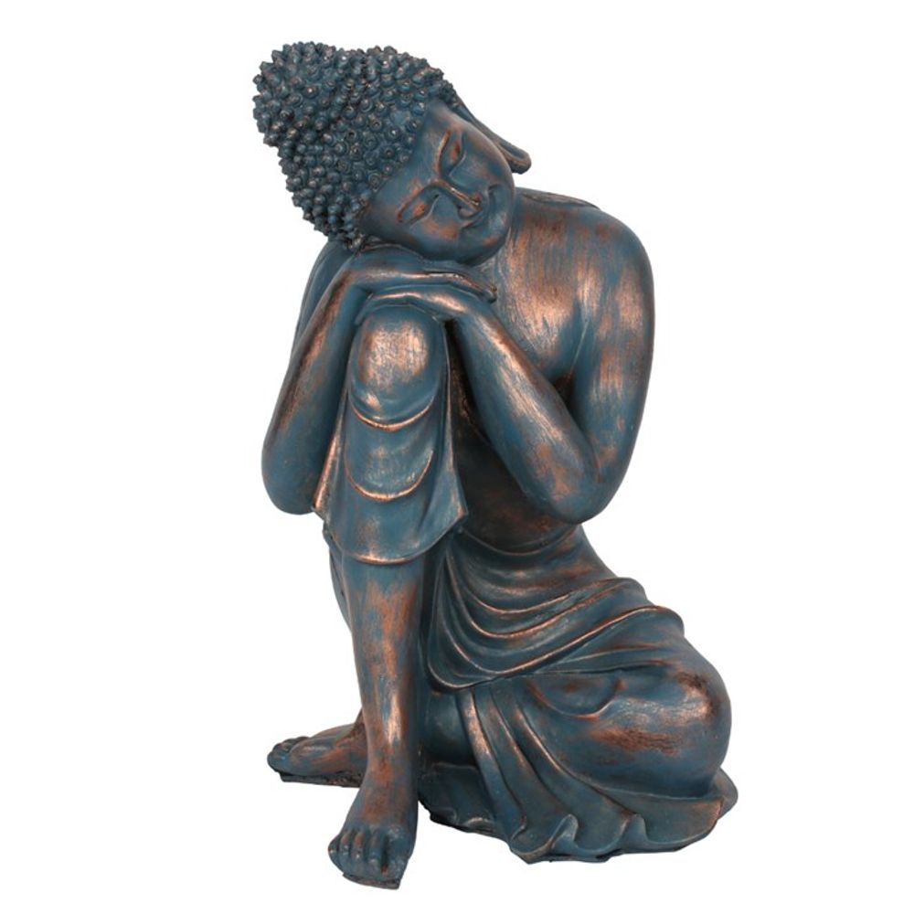 The Blue Hands on Knee Buddha features a tranquil figure with a teal patina finish, seated with legs folded and head resting gently on its knee, eyes closed in meditation. The robe drapes gracefully, and the detailed curls of the hair combined with copper accents make this stunning blue Buddha an enchanting focal point.