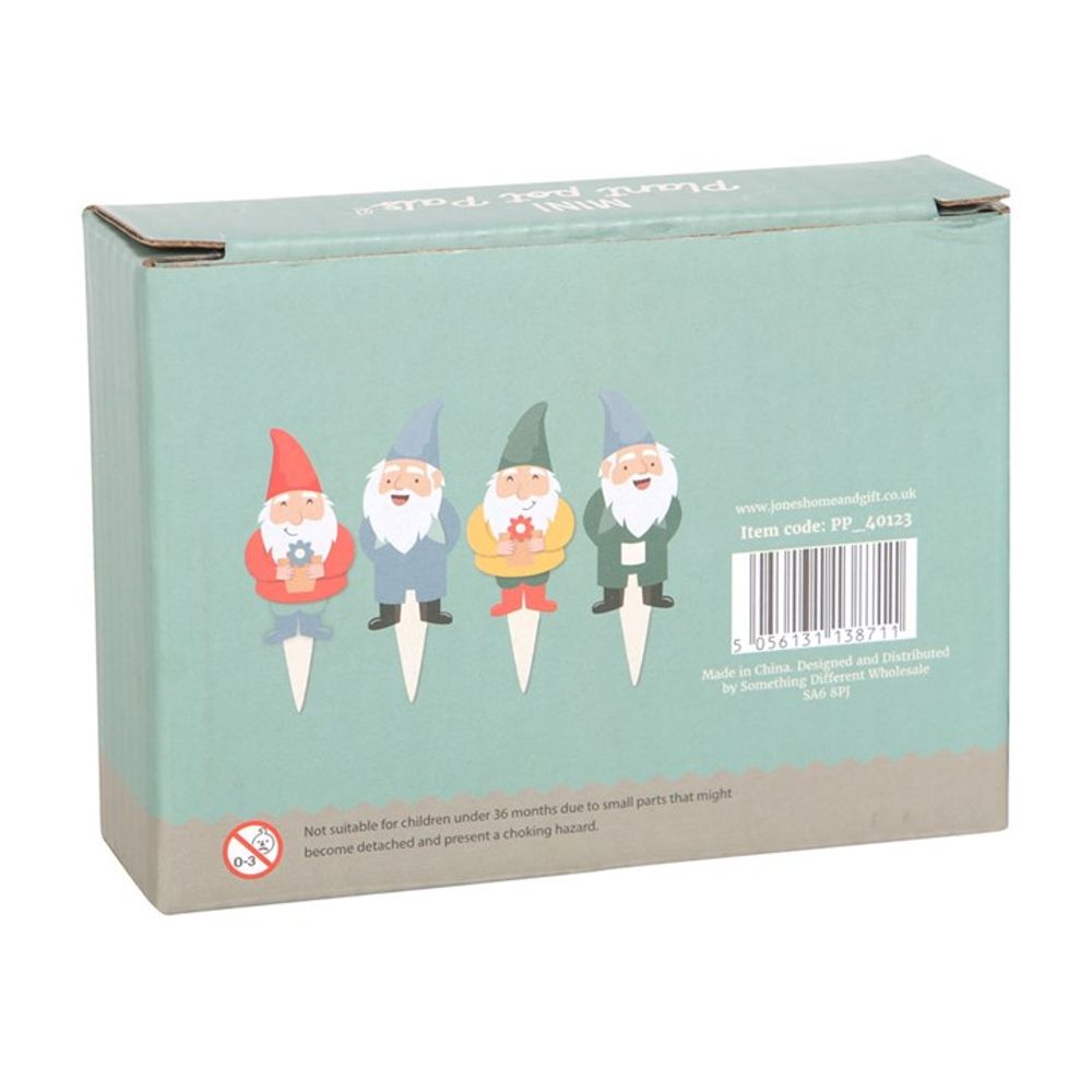 A rectangular green box featuring illustrations of the Set of 4 Mini Gnome Plant Pot Pals is shown. These charming mini garden gnome ornaments, ideal for fairy garden accessories or plant pot decorations, each hold a different item: a watering can, a flowerpot, a leaf, and a flower. An item code and safety warning are also visible on the box.