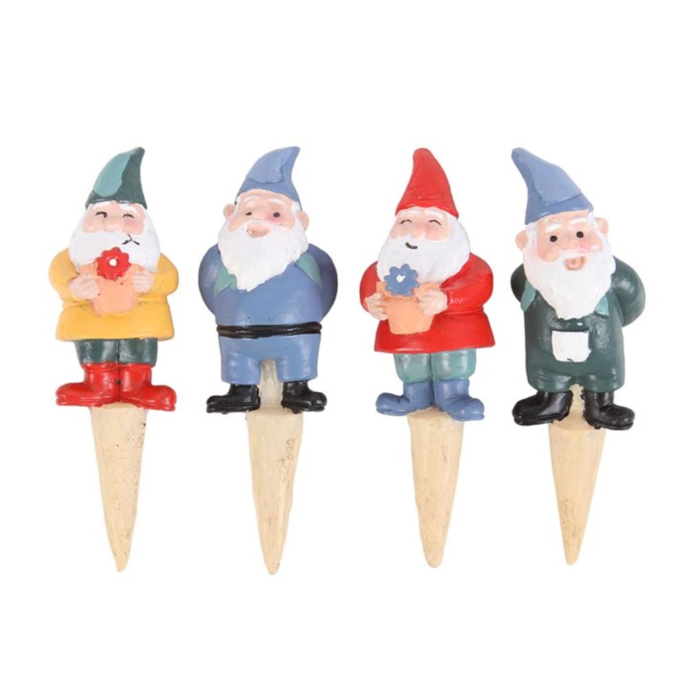 The Set of 4 Mini Gnome Plant Pot Pals features four charming garden gnome plant stakes, each standing in a row. Adorned with uniquely colored hats and outfits in yellow, blue, red, and green, these gnomes all boast white beards and hold small flowers. Ideal as fairy garden accessories or plant pot decorations, the pointed stakes are designed for easy insertion into soil.