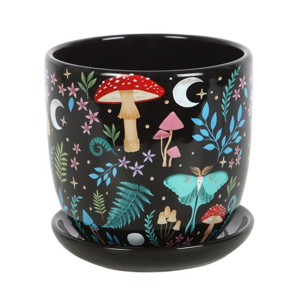 The Dark Forest Print Ceramic Plant Pot with Saucer features a black ceramic design adorned with vibrant flora and fauna, including red and pink mushrooms, moons, stars, ferns, blue butterflies, and various flowers. It's perfect for adding charm to your house plants.