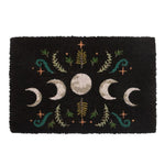 The Black Dark Forest Moon Phase Doormat features an enchanting design with a mystical moon phase, highlighting a full moon at its center bordered by waxing and waning crescent moons. The charming leafy floral patterns in green and orange stand out against the black background.