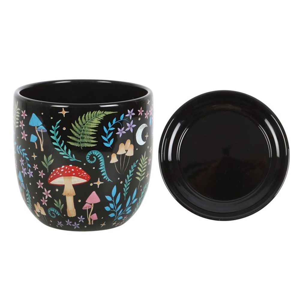 Dark Forest Print Ceramic Plant Pot with Saucer featuring colorful illustrations of mushrooms, ferns, stars, and a crescent moon. This whimsical design is inspired by nature and the motifs of flora and fauna. The pot comes with a matching black saucer placed beside it.