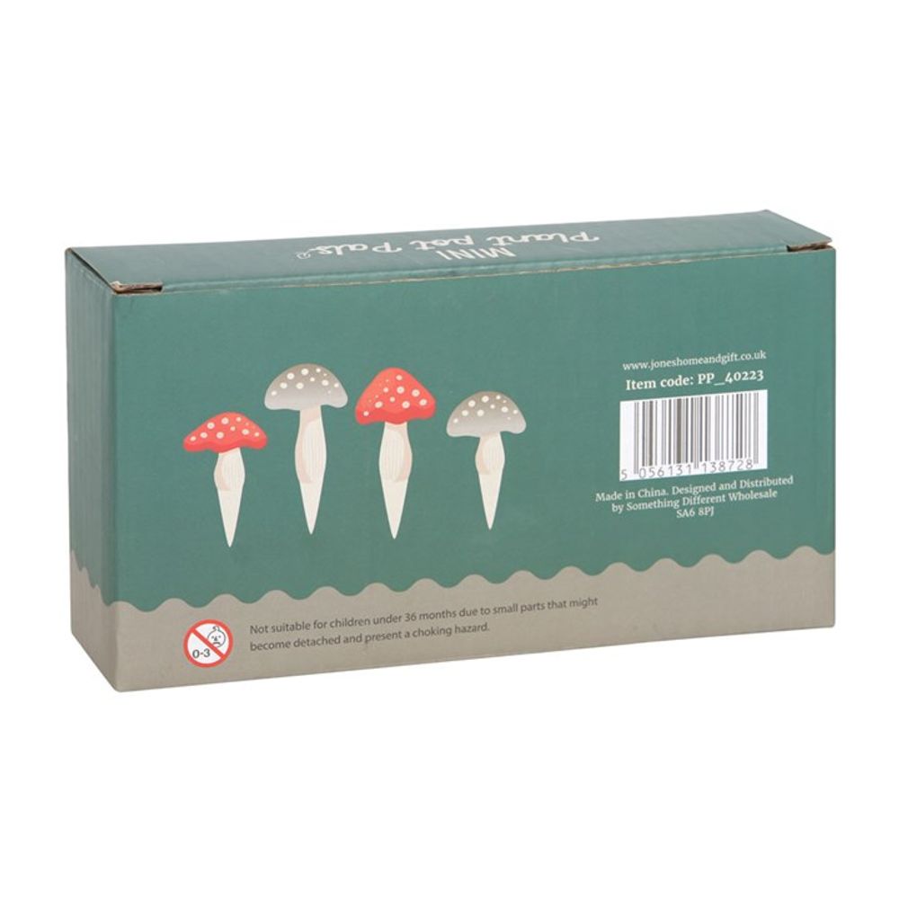 Introducing the Set of 4 Mini Mushroom Plant Pot Pals: a rectangular box featuring a charming green and beige design adorned with illustrations of various mushrooms, including some with iconic red caps and white spots. Ideal for decorating your fairy garden or plant pot, this set includes miniature toadstool ornaments. The packaging also notes that it contains small parts posing a choking hazard for children under 36 months.