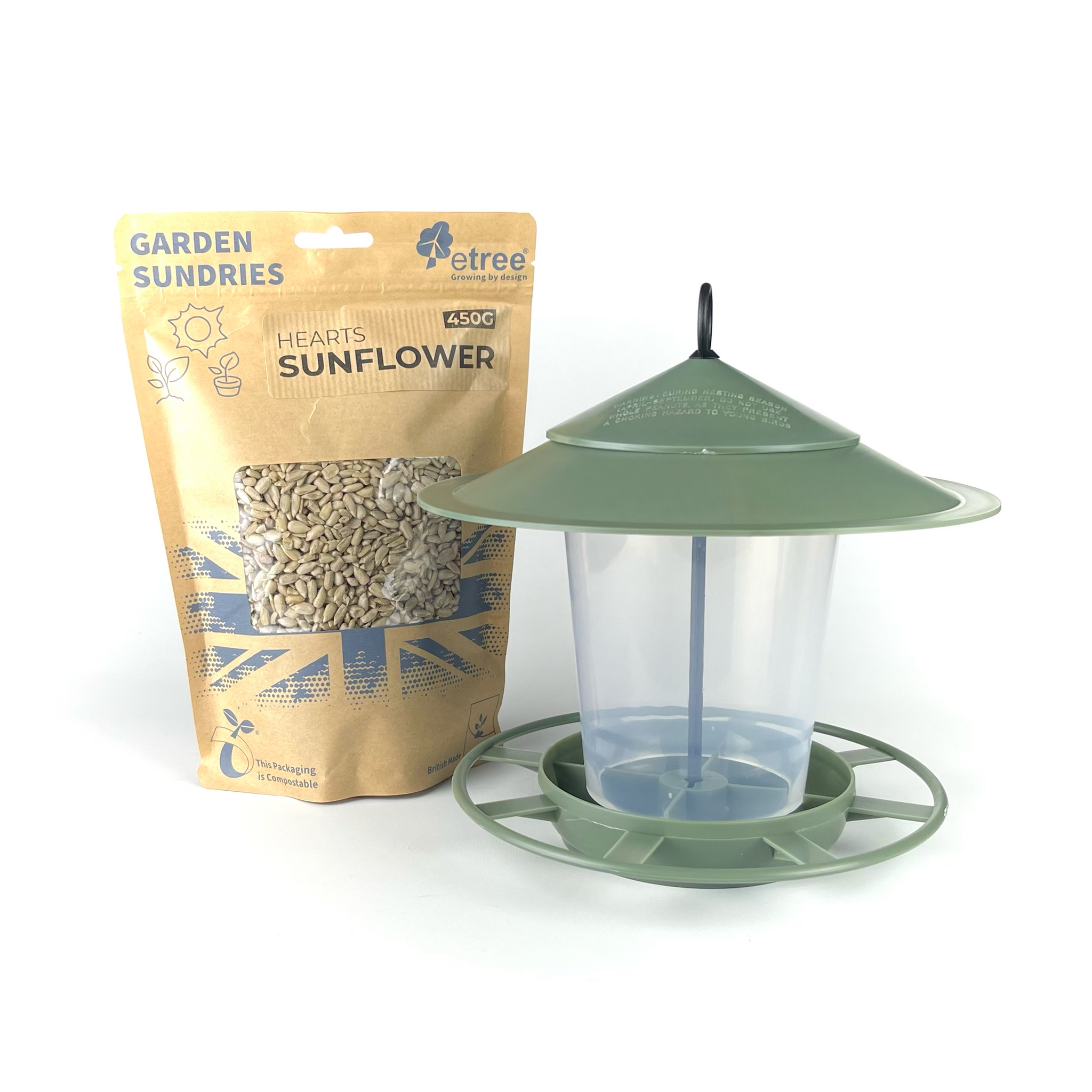 A slate green Pre-Filled Hanging Lantern Bird Feeder with a wide, sloped roof and circular perch base is positioned next to a 450g package of Sunflower Hearts wild bird seed. The tan package features a transparent window displaying the seeds inside. Both items are labeled "Garden Sundries" and are part of the Pre Filled Hanging Lantern Bird Feeder Gift Set & Sunflower Hearts Wild Bird Seed collection.