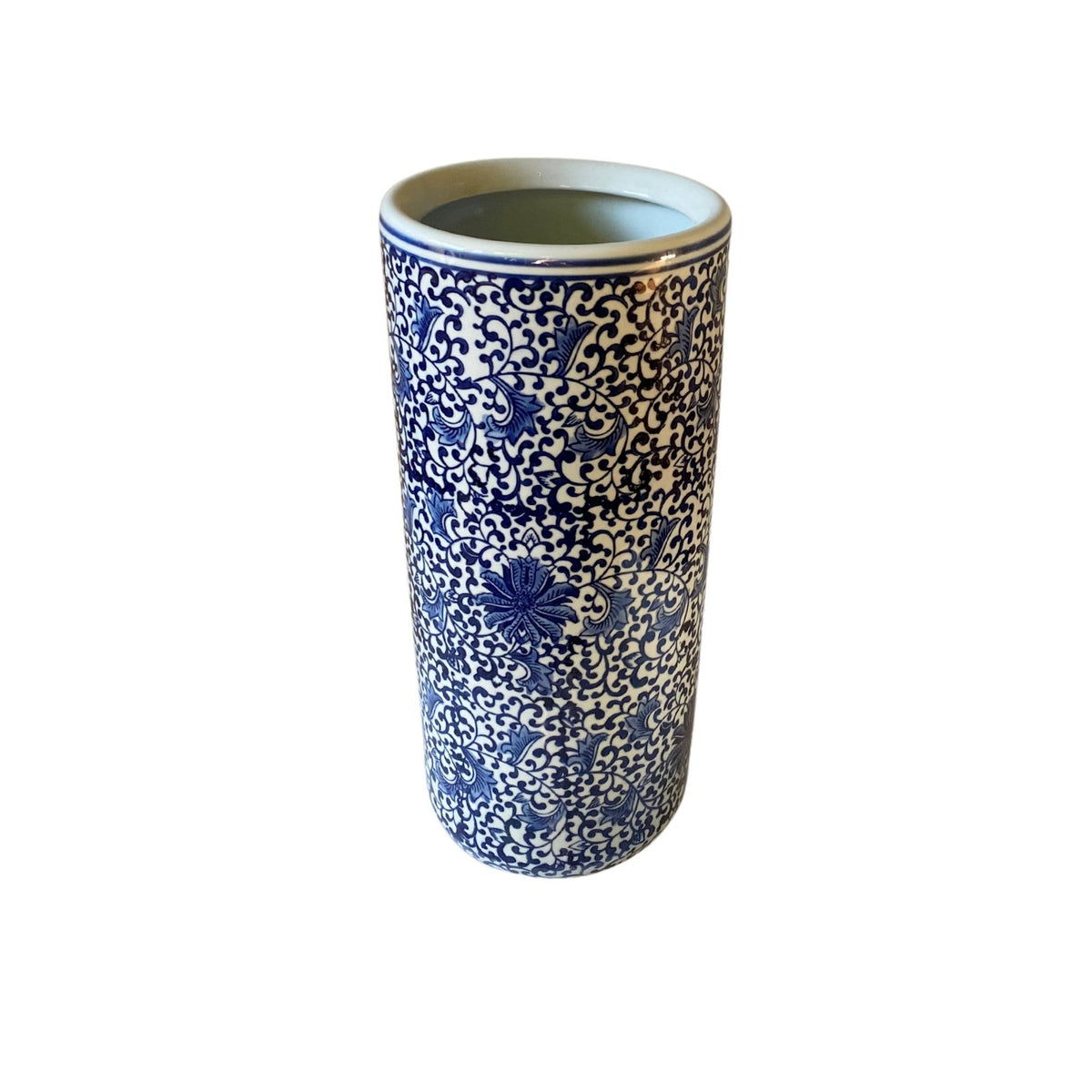 The White With Blue Floral Print Umbrella Stand is a tall, cylindrical ceramic vase featuring intricate blue floral motifs and a glossy finish on a pristine white background, doubling as an elegant umbrella stand.