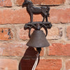 The Rustic Cast Iron Wall Bell, Horse, features a charming horse figure and hangs from a red brick wall with a short white rope—a perfect accent for farmhouse decor and horse enthusiasts.