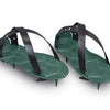 A pair of ProSpike Lawn Aerator Shoes featuring an enhanced strap design and four cross-shaped spikes on the soles. The black plastic adjustable straps ensure a secure fit over regular shoes, allowing the user to effortlessly aerate their lawn by walking on it.