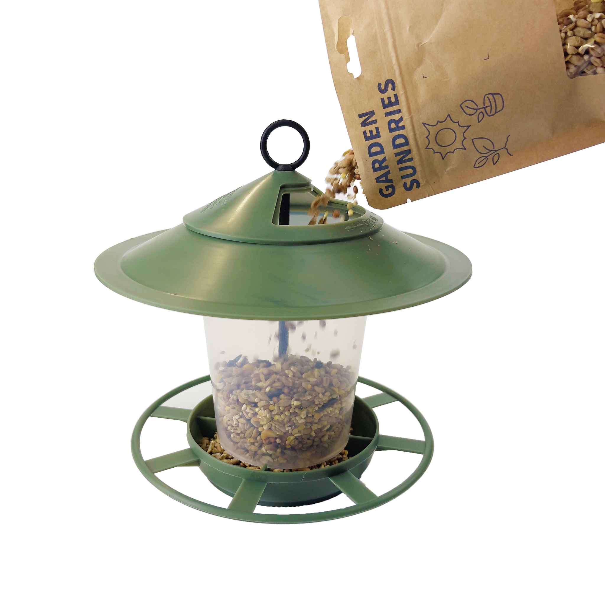 The Pre Filled Hanging Lantern Bird Feeder Gift Set & Sunflower Hearts Wild Bird Seed (450g) are ready for use. The green, easy-clean feeder with a circular base and a hook on top for hanging is being filled with sunflower hearts wild bird seed from a brown paper bag labeled "Garden Sundries." Seeds are falling from the bag into the feeder.