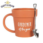 The Gardener of the Year Pot Mug and Shovel Spoon is an orange ceramic mug shaped like a plant pot, with "Gardener of the Year" inscribed on it. A miniature spade-shaped shovel teaspoon rests on the handle, featuring a "Gift of the Year 2021 Shortlisted" logo in the top left corner.